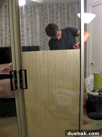 DIY privacy screen step 2: Taping grasscloth panel to sliding glass door frame.
