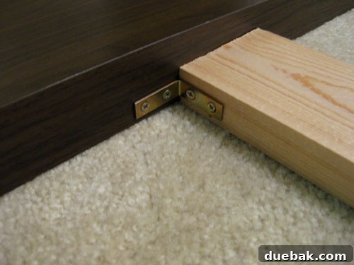DIY headboard assembly step 4: Attaching wooden legs to the Lack table headboard with L-brackets.