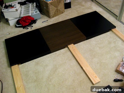 Close-up of L-brackets securing the wooden legs to the DIY Lack headboard.