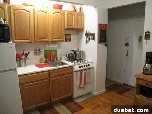 Before photo of the original cramped NYC kitchen, showing an old stove and fridge, and minimal cabinet space
