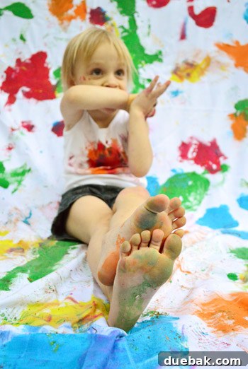 Clara sitting barefoot on the painted fabric, adding a natural touch to her birthday photos