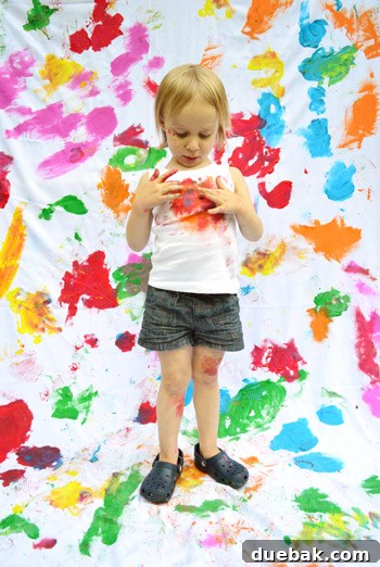 Clara admiring the colorful paint splatters on her shirt with a proud look