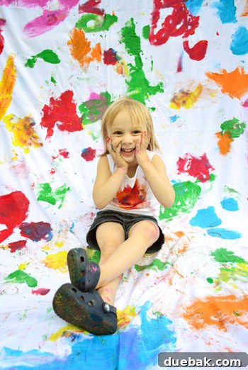 Clara with paint playfully smeared on her face, smiling brightly
