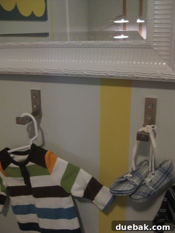 A foldable hook in the process of being folded upwards against the nursery wall.