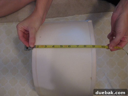 DIY Fabric Lamp Shade Makeover 6 Fabric laid out on a table, with a tape measure showing measurements for the lampshade.