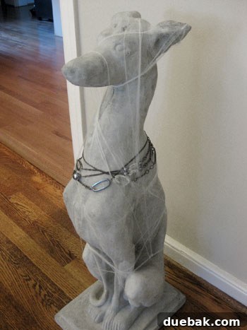 Concrete greyhound statue decorated with a necklace and spiderwebs