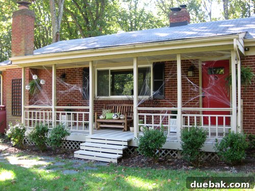 Spooky Halloween porch decorated with black branches and white pumpkins