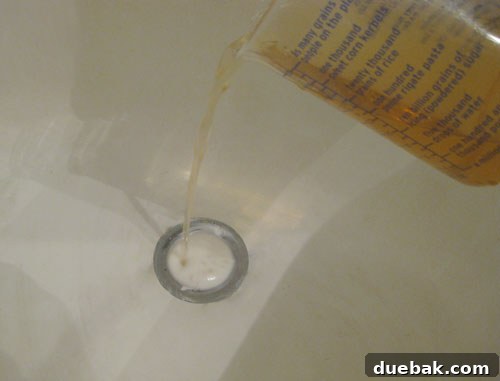 pouring vinegar and baking soda in clogged bathroom drain