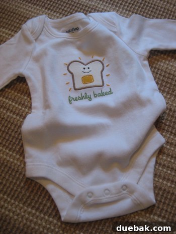 A 'freshly baked' baby onesie, used for the family pregnancy reveal, held proudly by John.