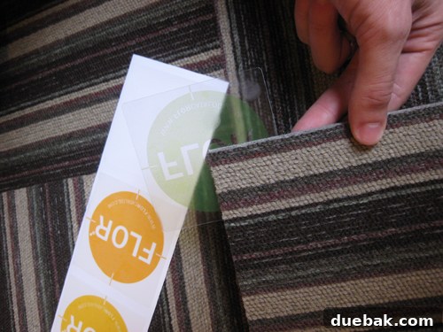 Close-up of Flor modular carpet tiles being installed, showing the simple sticky circles connecting the corners for easy assembly.
