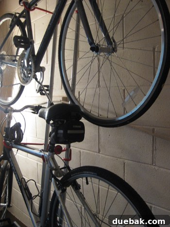 Vertical balancing bike rack holding two bikes against a cinder block wall, showcasing a smart space-saving storage solution.
