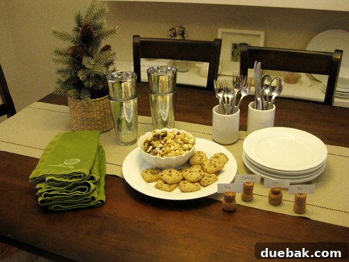Casual and inviting Thanksgiving table setting featuring gleaming metallic cups, a charming faux-spruce tree in a basket, and irresistible sweet treats like caramel corn and cookies, perfect for informal gatherings.