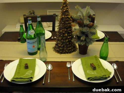 Rustic yet modern Thanksgiving table setting featuring a brown feather tree, a small pine cone tree, refreshing mini Pellegrino bottles, and unique wood block letters serving as personalized place cards.