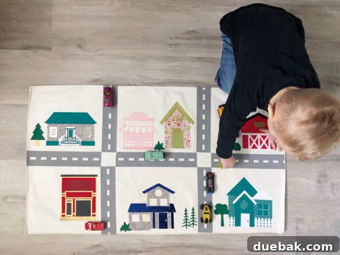 Build Your Own Adventure Car Play Mat with Cricut Maker 7 Child happily playing with toy cars on a colorful DIY car play mat made with Cricut Maker.