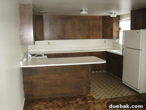 Goodbye Carpet, Hello White Kitchen 2 Before kitchen renovation showing dark, dated cabinetry, and a heavy, uninviting atmosphere with brown carpet