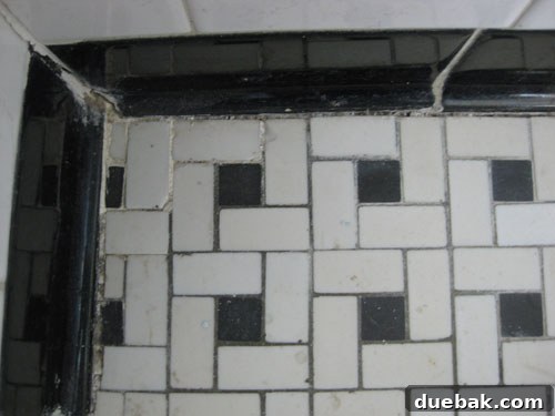 Sourcing Bathroom Tiles, Vanities, and Accessories 3 Close-up of severely cracked and stained black and white basketweave floor tiles in an old bathroom.