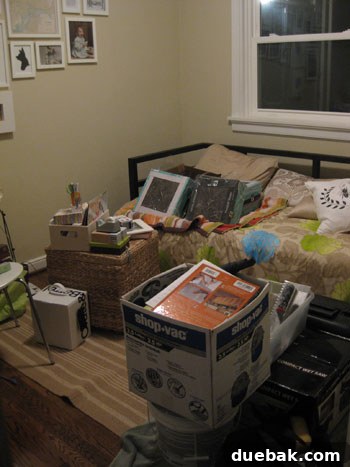 Cluttered spare bedroom, full of tools and demolition debris from a bathroom renovation