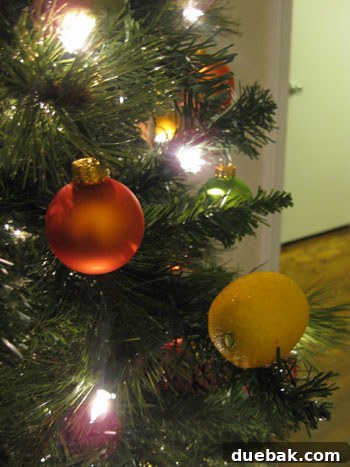 Crafting Radiant Dried Orange Ornaments 10 A close-up of faux lemons wired onto a Christmas tree branch, blending seamlessly with the green foliage and other ornaments.