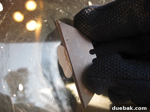 Person carefully scraping window with a razor blade