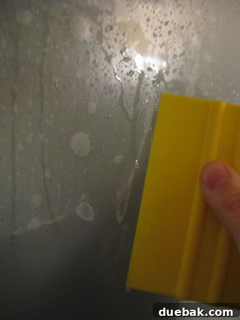 Person using a squeegee to smooth out window film