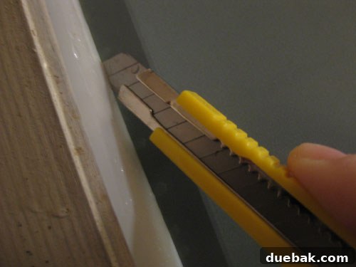 Close-up of a person trimming excess window film with an X-Acto knife