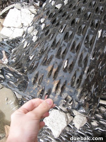 Close-up of the thick, heavy-duty metal mesh (lath) embedded in mortar, exposed during demolition.