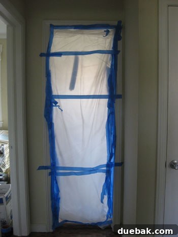 A thick plastic drop cloth sealed over a doorway, isolating the demolition zone from the rest of the house.