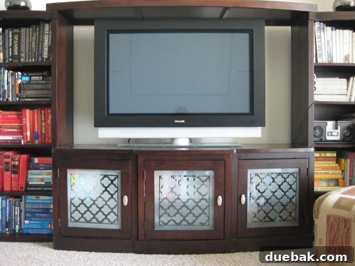 After DIY entertainment center makeover with beautifully frosted and stenciled glass doors, hiding clutter
