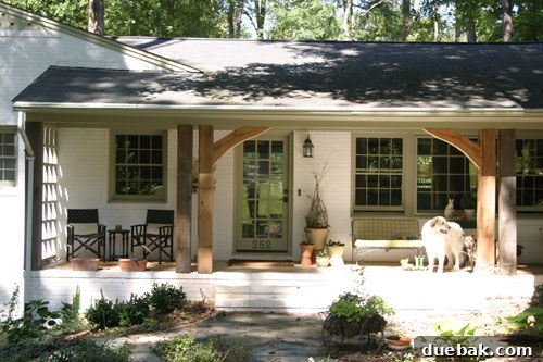 Finished French Country cottage exterior after renovation, featuring beautifully limewashed brick, impressive new oak posts, stunning hand-carved arches, and a stylish new front door, embodying rustic elegance.