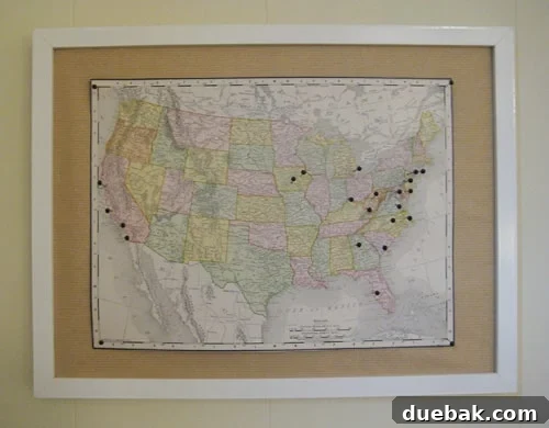 A beautifully framed vintage world map mounted on cork, adorned with numerous colorful pins marking past travel destinations, including a memorable Texas road trip.
