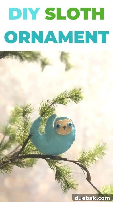 A close-up of the finished felt sloth ornament hanging with other Christmas decorations.