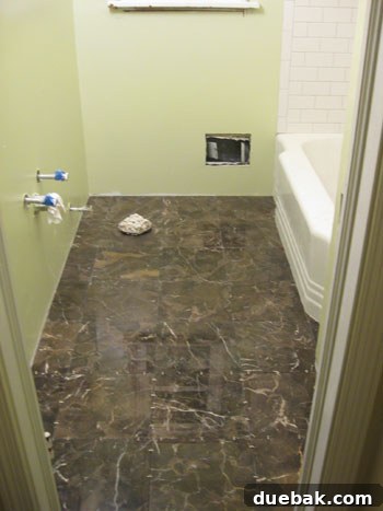 Elevate Your Bathroom Renovation with Flawless Baseboard and Trim Installation 2 Tiled bathroom floor before baseboard installation, showing raw wall edges.