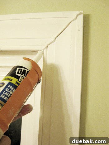 Elevate Your Bathroom Renovation with Flawless Baseboard and Trim Installation 11 Applying a bead of caulk along the corner seam of the window trim.
