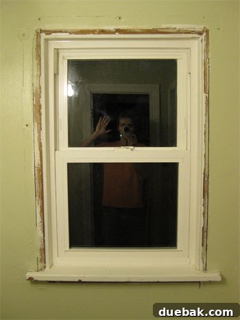 Elevate Your Bathroom Renovation with Flawless Baseboard and Trim Installation 3 Window frame after old trim removal, exposing the rough wall and gaps.