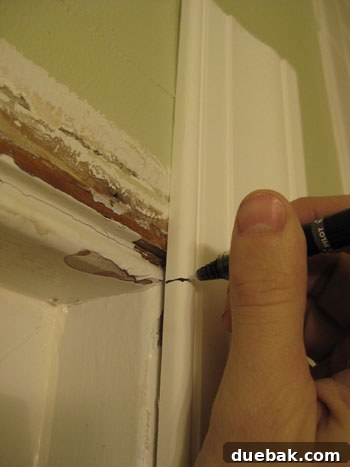 Elevate Your Bathroom Renovation with Flawless Baseboard and Trim Installation 4 Marking a trim piece with a ballpoint pen for a precise miter saw cut.