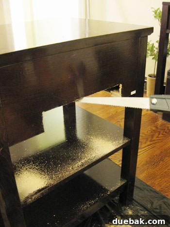 Cutting the back panel of the nightstand for plumbing