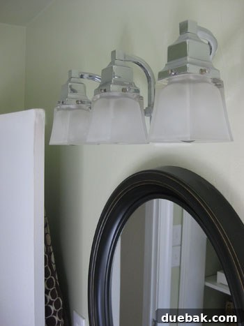 Close up of a bathroom light fixture with glass covers and screws
