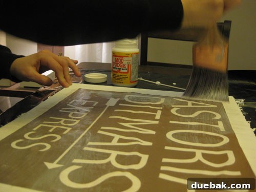 Crafting Vintage Wood and Paper Wall Signs 11 Mod Podge being applied over a printed sign on wood