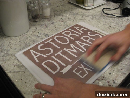 Crafting Vintage Wood and Paper Wall Signs 7 Damp sponge being rubbed over a printed design on a textured cutting board