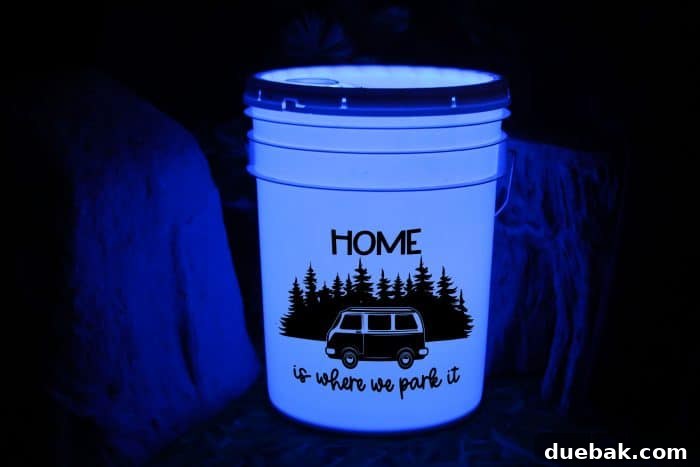 A beautifully illuminated DIY camping bucket light, showcasing a personalized 'Home Is Where You Park It' SVG design. The bucket provides a warm, inviting glow, perfect for any campsite. This image highlights the aesthetic appeal and customization potential of the project.