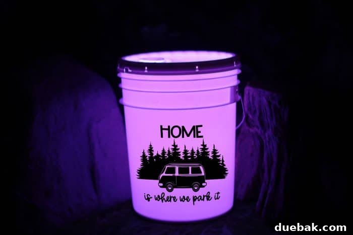 A camping bucket light illuminating a campsite at dusk. The bucket features a detailed vinyl design and casts a warm, welcoming light, enhancing the overall camping experience. This image emphasizes the practical application and ambiance provided by the DIY project.