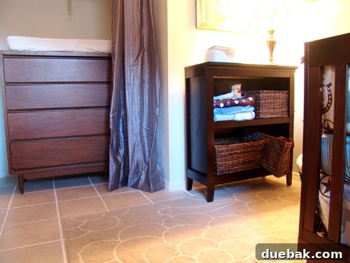 Nursery corner with vintage dresser, changing pad, and shelves with books.