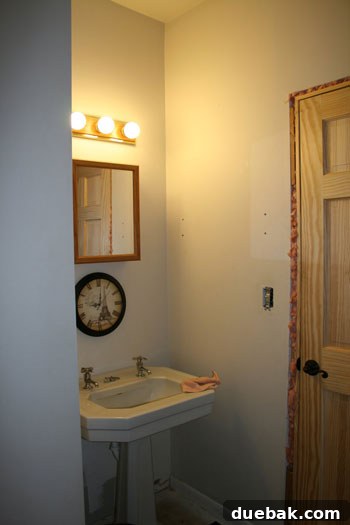 Subtle Stripes, Stenciled Style: Revamping Your Bathroom 3 Another view of the bathroom before renovation, highlighting the original fixtures and color scheme.