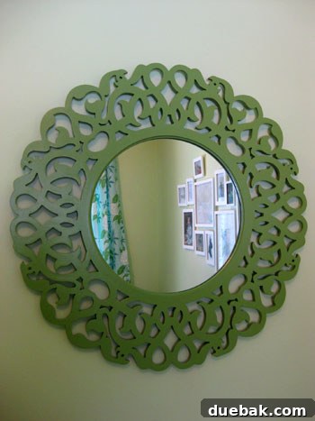 The newly painted green mirror securely hung on the wall in a nursery, reflecting light from a window and enhancing the room's decor.