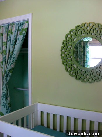 Close-up of the green painted mirror in the nursery, highlighting the intricate frame details and the smooth, even paint finish.