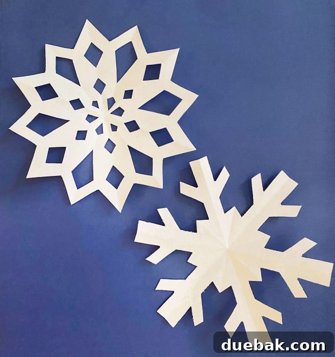 Two intricately cut paper snowflakes displayed against a light background, highlighting the delicate details and perfect symmetry achievable with templates.