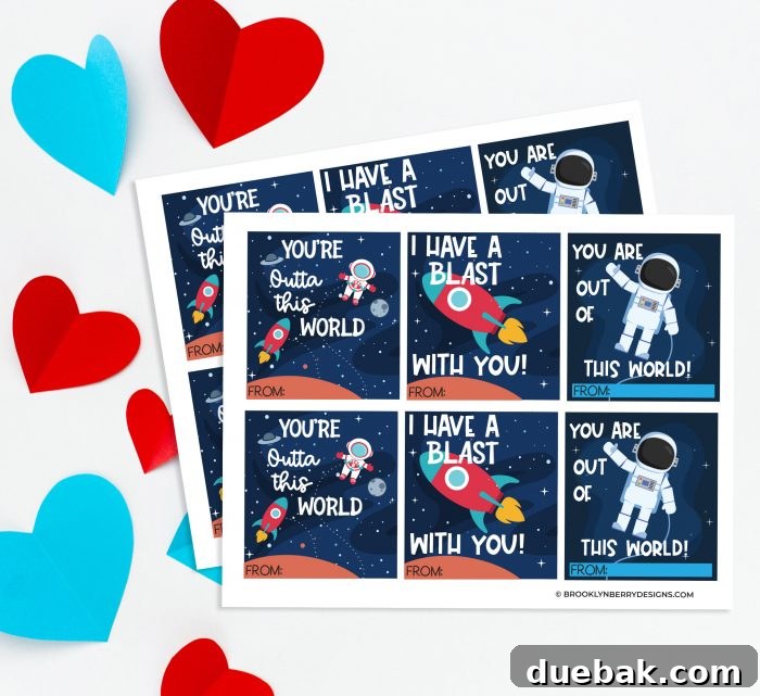 Assorted space-themed valentine cards laid out on a table, ready for cutting, alongside crafting supplies.