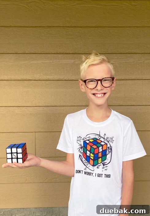 Unlock Sublimation Printing with Your EcoTank 18 A child proudly wearing a custom-sublimated t-shirt featuring a Rubik's Cube design.