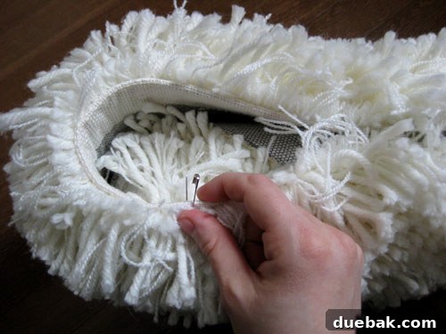 The shag rug pillow being secured with safety pins, cleverly hidden within the dense fibers.
