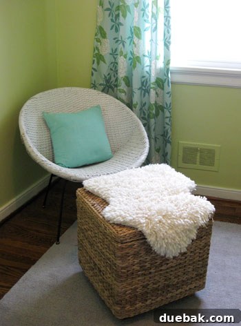 A faux sheepskin rug placed on a square ottoman in a nursery, showcasing its versatility.